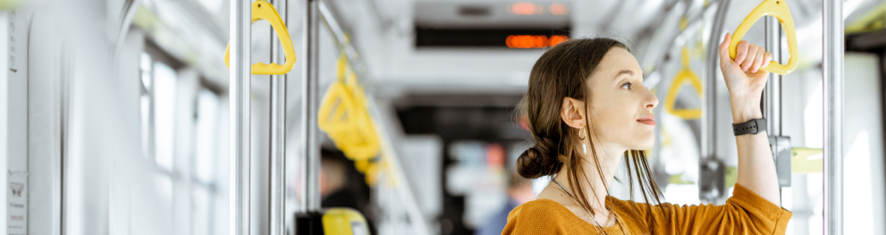 Woman standing in a bus looking out of the window.