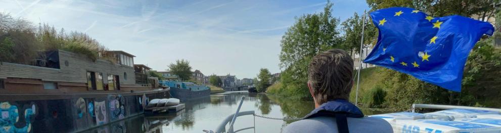 Man steering a boat with a large EU flag in front.