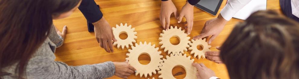 People puzzling cogwheels together on a table.