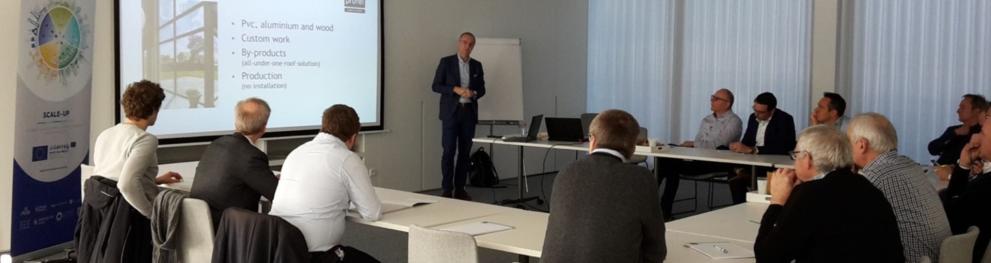 Presenter and small audience in a meeting room with a large screen