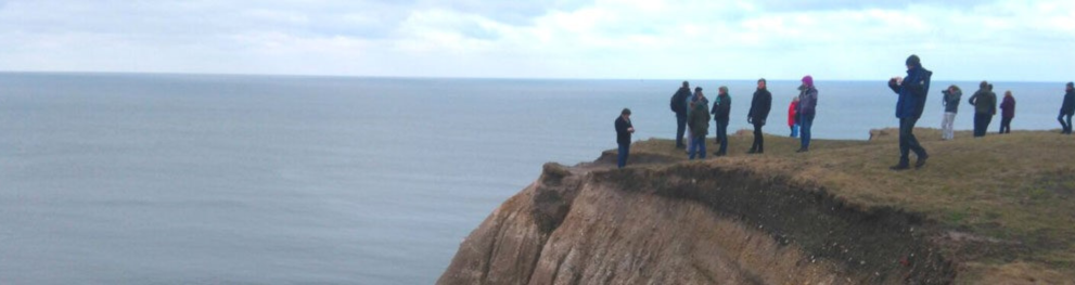 People standing on cliff looking out on the sea