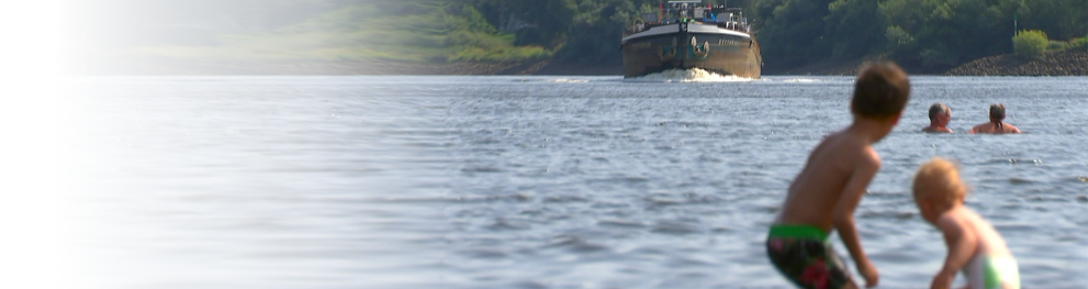 Recreational lake with children in the water and a boat arriving