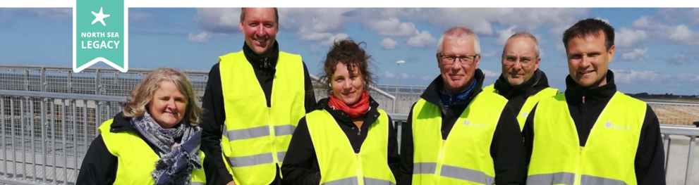 Group of smiling people wearing yellow safety vests