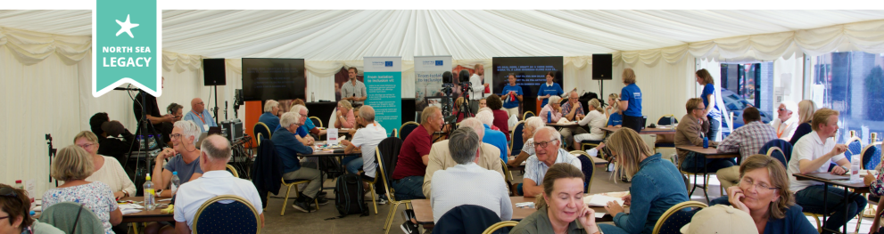 People gathered in a tent discussing around tables.