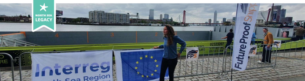 Large banner including an EU flag and an Interreg North Sea logo displayed next to the sea at a city harbour.