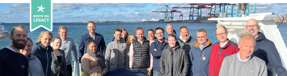 A group of people standing next to the sea in a harbour environment.