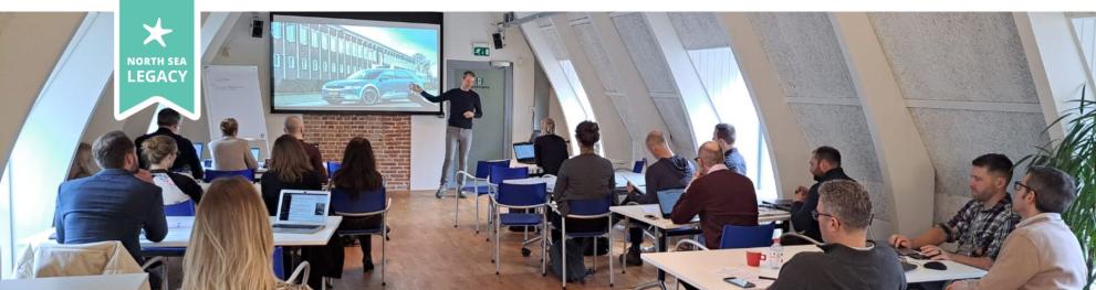 People watching a presentation in a beautiful white room filled with light. 