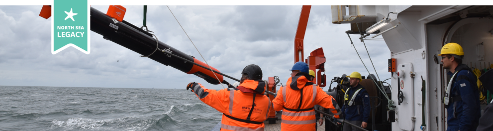 Scientists handling equipment on board a ship in stormy weather.