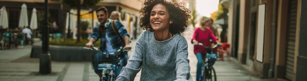 A happy lady on a bike in a busy street.