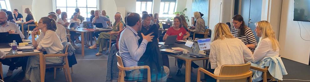 People sitting at roundtables in a large sunny room.