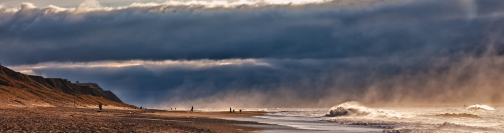 A coastal landscape set against a dramatic stormy sky.