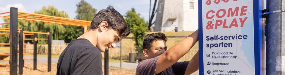 Photo of sport sharing station being used by two teenagers, one holding weights he has just borrowed