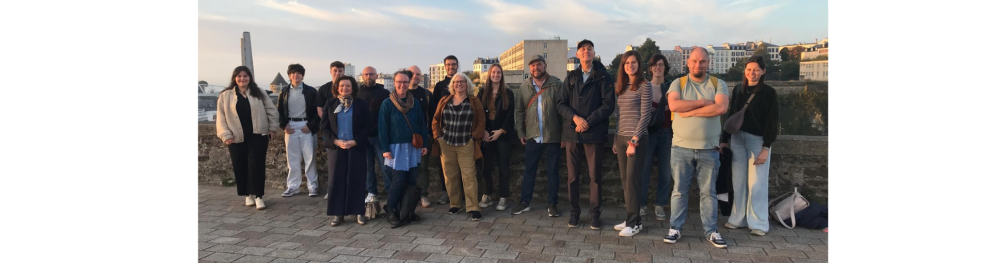 The SMALL partner pose together for a picture. In the background, Brest's morning sky