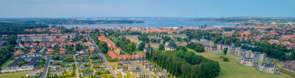 Aerial photo of Middelfart city with the sea and a suspension bridge in the horizon.