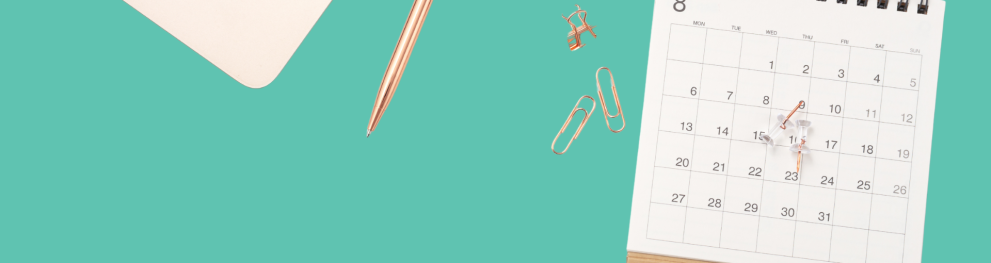 A calendar with a pen and paper clips on a green background. 