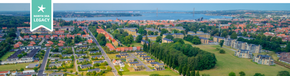Aerial photo of Middelfart city with the sea and a suspension bridge in the horizon.