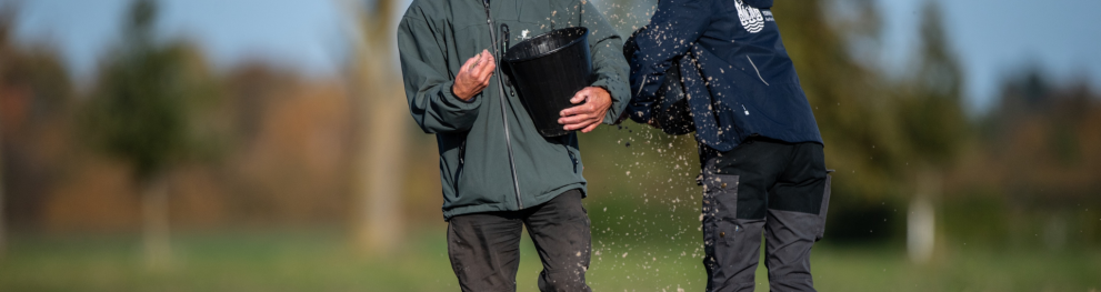 Photo of two Aarhus volunteers scattering seeds over fields