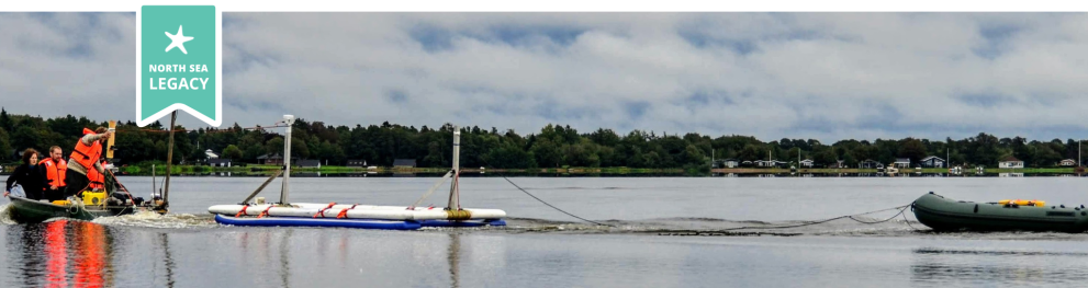 A lake with a boat in tow, followed by a small boat with people wearing orange fests.